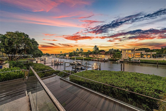 deck at dusk with a water view and a dock