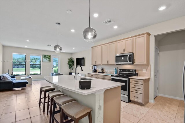 kitchen featuring a center island with sink, light tile patterned floors, sink, and appliances with stainless steel finishes