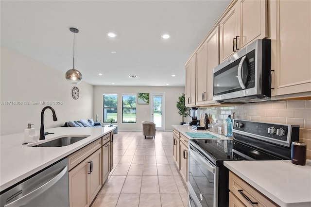 kitchen featuring stainless steel appliances, hanging light fixtures, sink, and backsplash