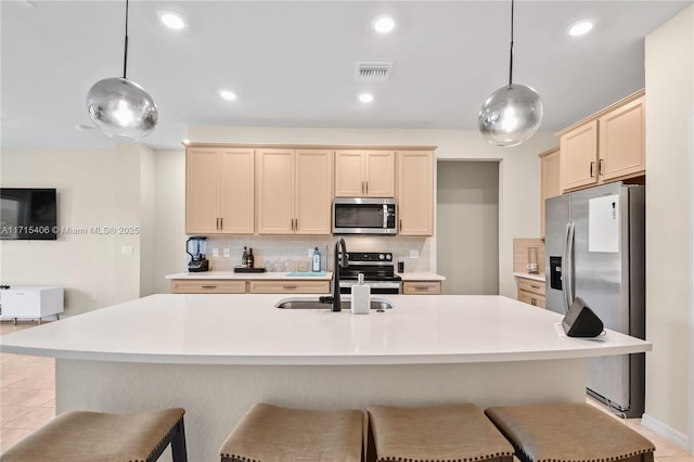 kitchen featuring appliances with stainless steel finishes, sink, a center island with sink, and decorative light fixtures