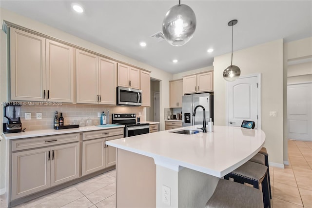 kitchen with a kitchen island with sink, sink, pendant lighting, and stainless steel appliances