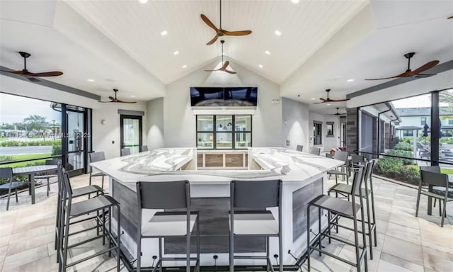 kitchen with lofted ceiling, light stone countertops, and a large island with sink