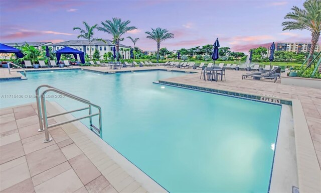 pool at dusk featuring a patio