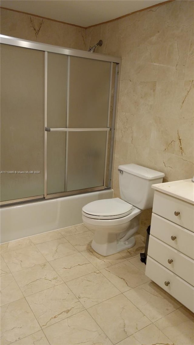 bathroom with toilet and shower / bath combination with glass door