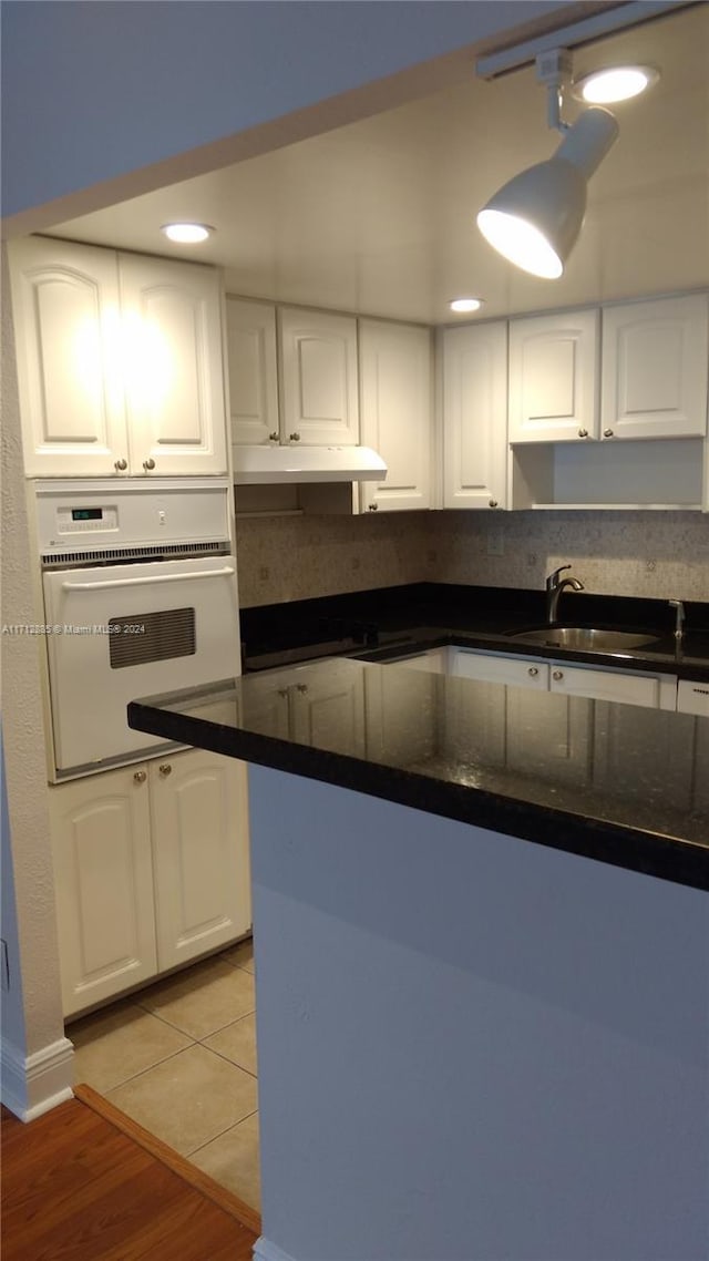 kitchen featuring white cabinetry, sink, light tile patterned floors, and white oven