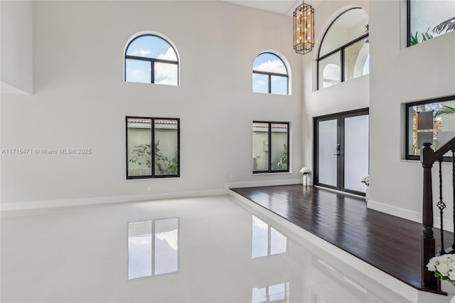 entrance foyer featuring a notable chandelier, a towering ceiling, hardwood / wood-style floors, and french doors