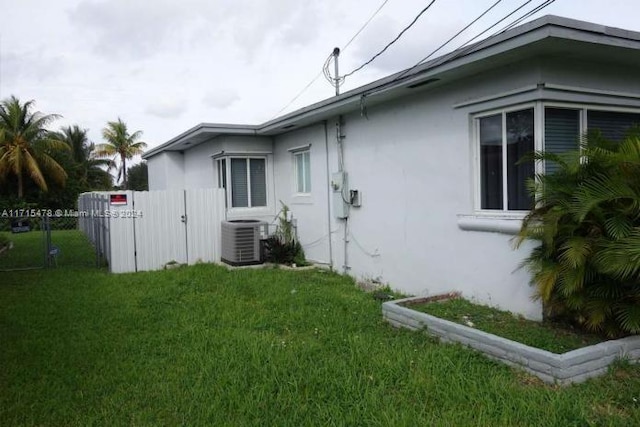 view of side of property featuring a lawn and cooling unit