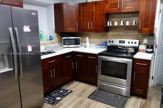 kitchen with appliances with stainless steel finishes, backsplash, and light hardwood / wood-style floors