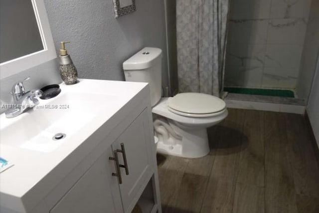 bathroom featuring a shower with shower curtain, vanity, hardwood / wood-style flooring, and toilet