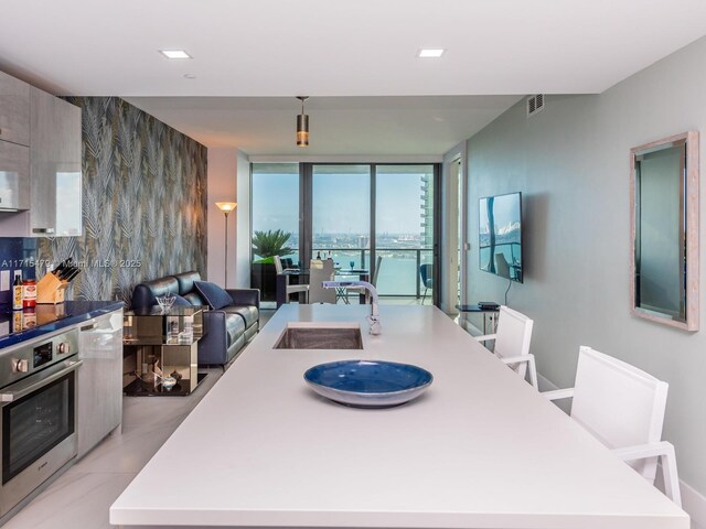 kitchen featuring a large island, expansive windows, oven, and light tile patterned floors