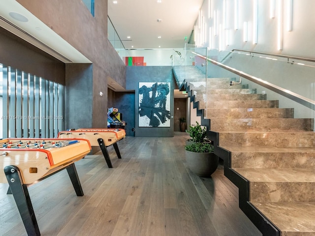 recreation room with hardwood / wood-style flooring and a towering ceiling