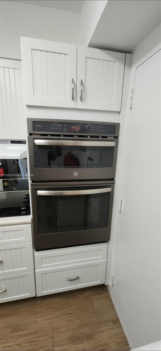 kitchen featuring dark wood-style floors, stainless steel double oven, and white cabinets