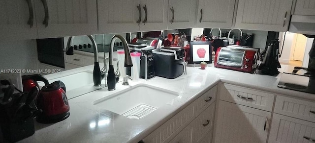 kitchen featuring white cabinets, light countertops, and a sink