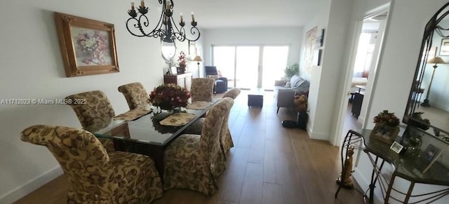 dining space with a notable chandelier, baseboards, and wood finished floors