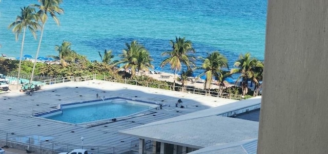 view of swimming pool featuring a water view and fence