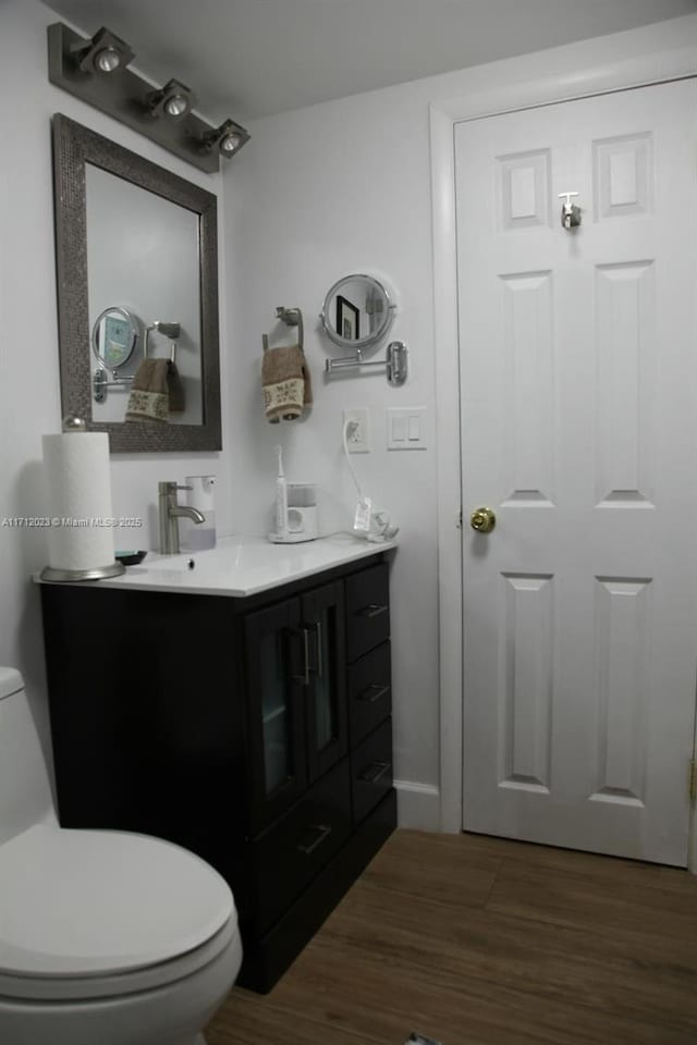 bathroom featuring toilet, wood finished floors, and vanity