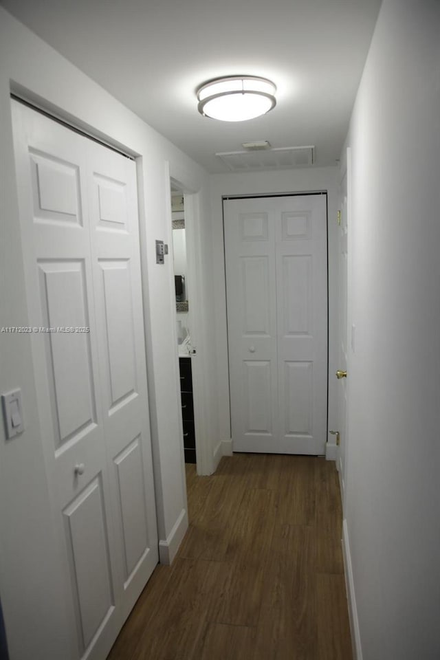 corridor with baseboards and dark wood finished floors