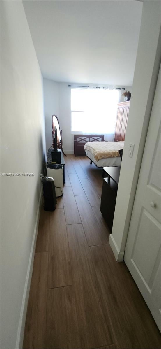 hallway with baseboards and dark wood-style flooring