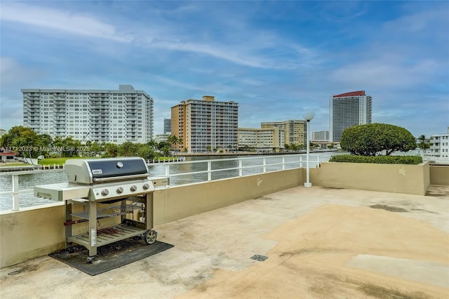 view of patio with a city view, a water view, and an outdoor kitchen