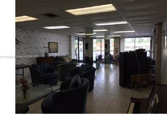 living room featuring a paneled ceiling, wallpapered walls, light tile patterned floors, and visible vents