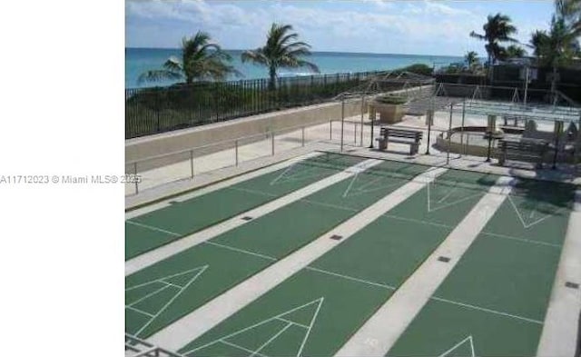 view of community with shuffleboard, a water view, and fence