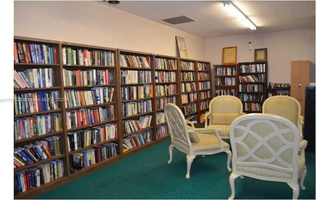 sitting room featuring bookshelves and carpet flooring