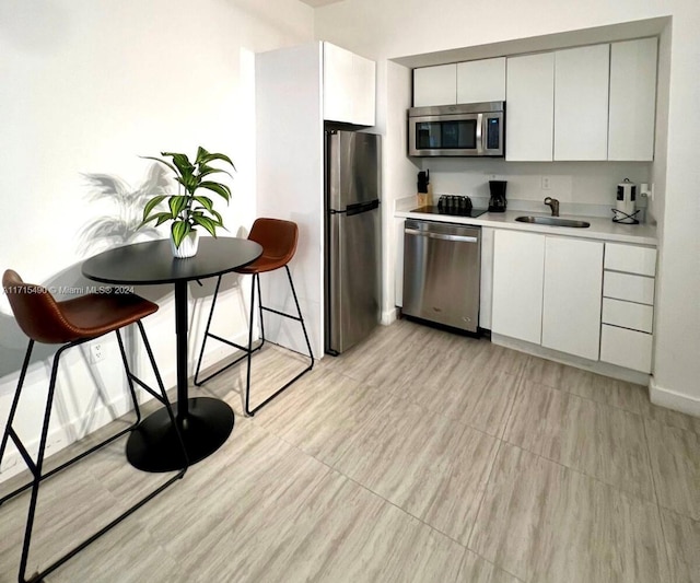 kitchen featuring white cabinets, a breakfast bar, sink, and stainless steel appliances