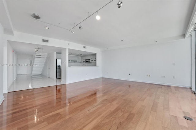 unfurnished living room featuring light wood finished floors, baseboards, and visible vents