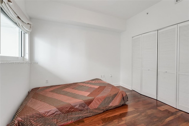 bedroom with dark hardwood / wood-style floors and a closet