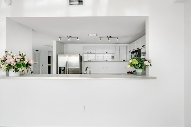 kitchen with white cabinetry, sink, stainless steel fridge with ice dispenser, and kitchen peninsula