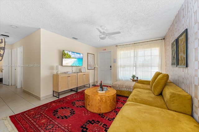 living room with ceiling fan, light tile patterned floors, and a textured ceiling