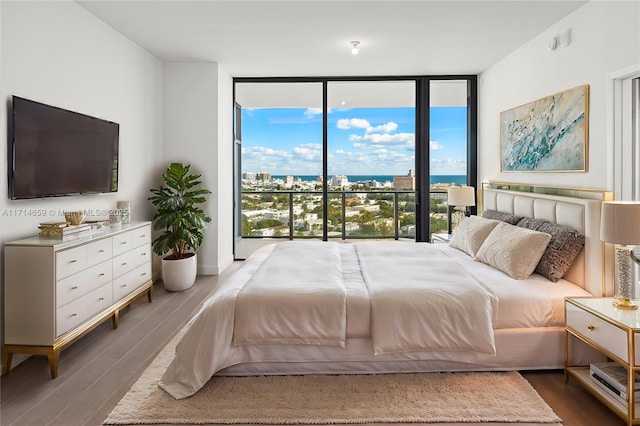 bedroom with expansive windows, hardwood / wood-style flooring, and access to exterior