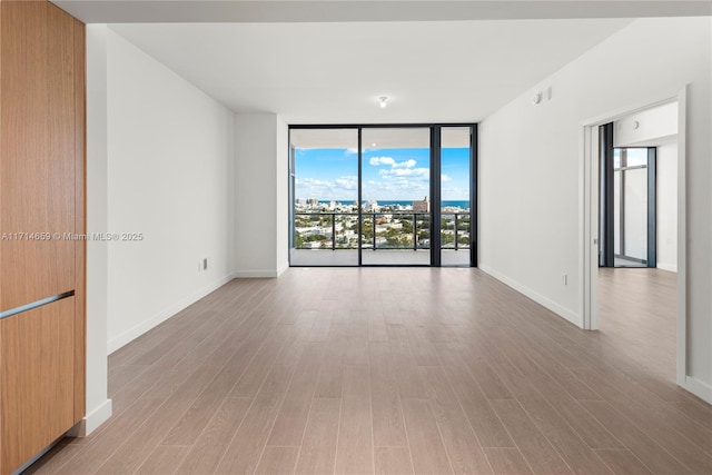 unfurnished room with floor to ceiling windows and light wood-type flooring