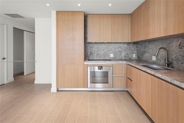 kitchen with light brown cabinetry, sink, backsplash, oven, and black electric stovetop