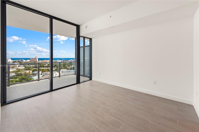 unfurnished room featuring a water view, floor to ceiling windows, and wood-type flooring