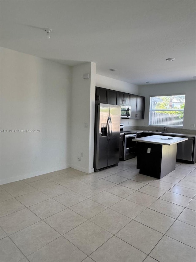 kitchen with a center island, sink, light tile patterned floors, and stainless steel appliances