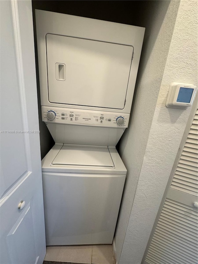 laundry room with stacked washing maching and dryer and light tile patterned floors