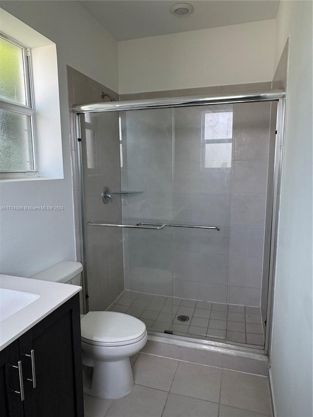 bathroom with tile patterned flooring, vanity, an enclosed shower, and toilet