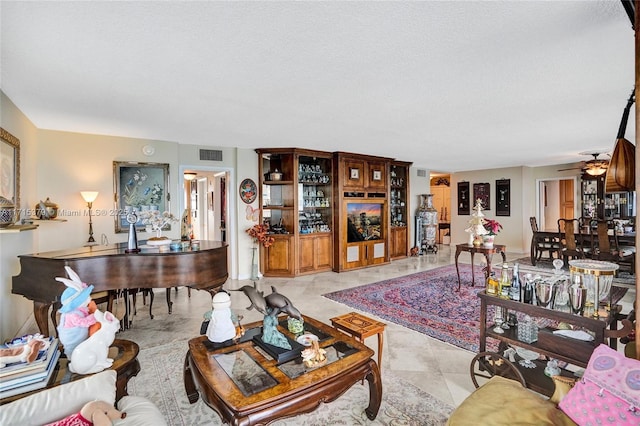 living room with ceiling fan and a textured ceiling