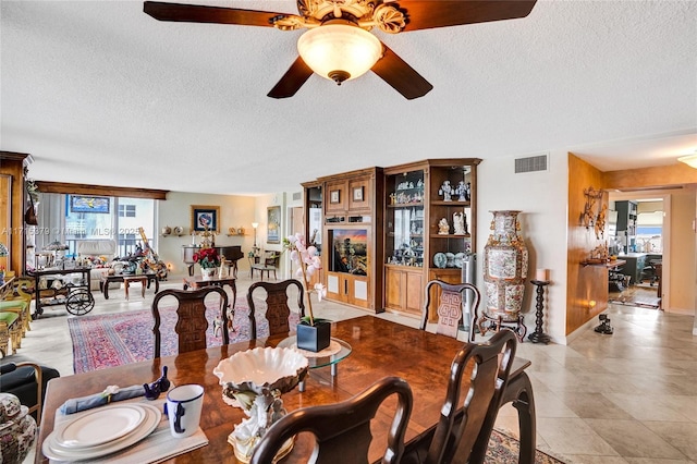 dining area with a textured ceiling and ceiling fan