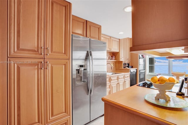 kitchen featuring sink, double wall oven, stainless steel refrigerator with ice dispenser, and a water view