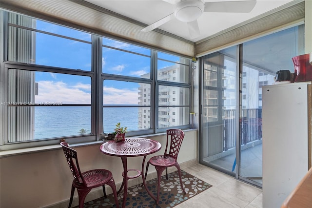 sunroom / solarium featuring ceiling fan and a water view