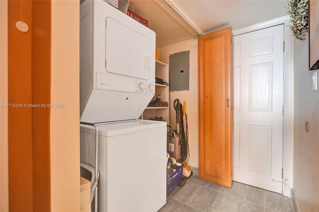 laundry room featuring electric panel, stacked washer and dryer, and light tile patterned flooring