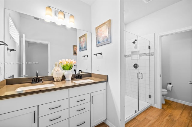 bathroom with wood-type flooring, toilet, a shower with door, and vanity