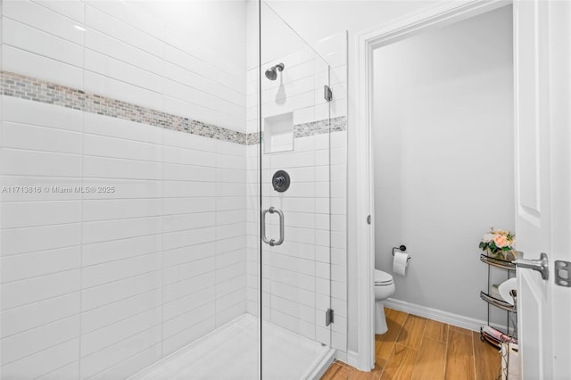 bathroom featuring walk in shower, hardwood / wood-style floors, and toilet