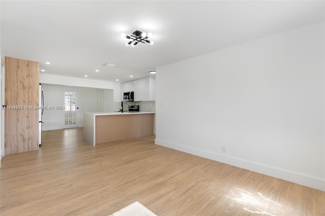 interior space with light brown cabinets, kitchen peninsula, appliances with stainless steel finishes, white cabinets, and light wood-type flooring