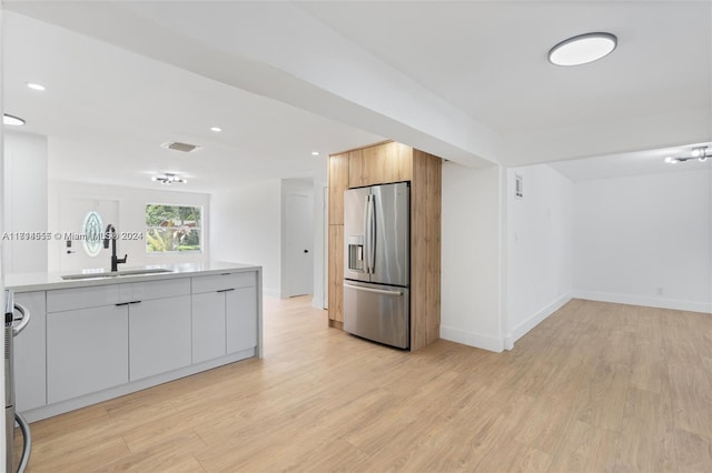 kitchen with white cabinets, stainless steel refrigerator with ice dispenser, light hardwood / wood-style flooring, and sink