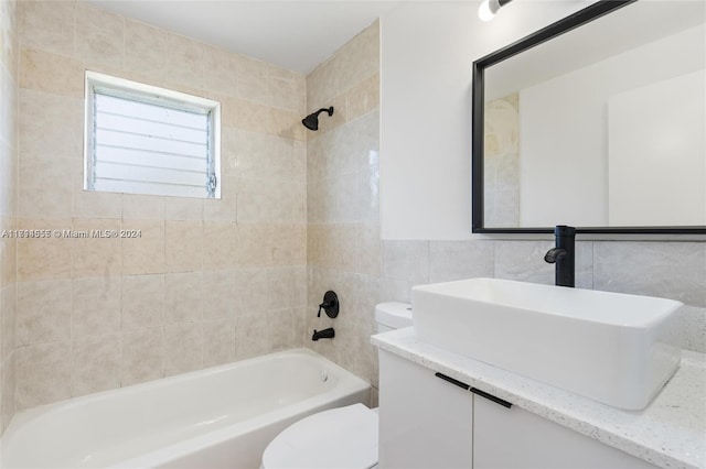 full bathroom with vanity, toilet, tile walls, and tiled shower / bath combo