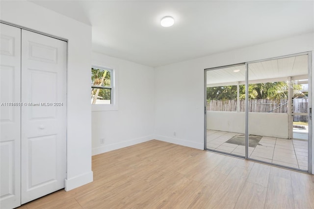 unfurnished bedroom with access to exterior, a closet, and light hardwood / wood-style flooring