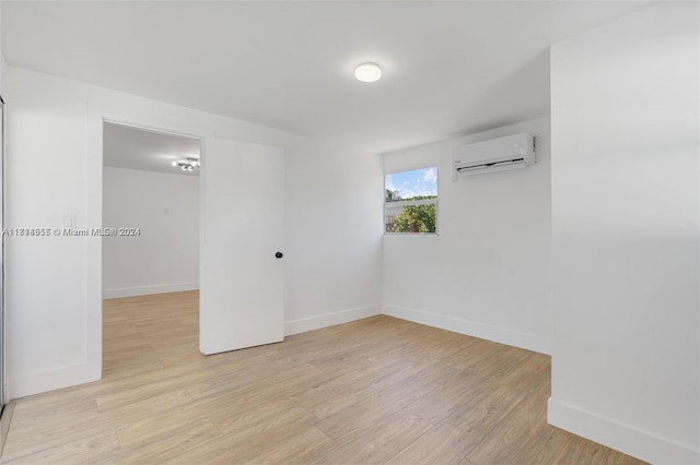 spare room featuring light wood-type flooring and an AC wall unit